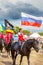 Solemn entry of a group of horse racing with flags in the meadow of the festival