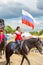 Solemn entry of a group of horse racing with flags in the meadow of the festival