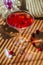 Solemn rustic still life with glass of red drink with autumn berries and white flowers on wooden table and textile in striped