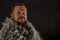 Solid bearded man in a fur mantle studio portrait