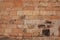 Solid brick wall. Orange bricks closeup. Weathered grungy brick wall photo background. Distressed texture of brickwork