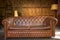 Solid leather sofa in a wooden interior. Brown color couch in home or office loft style interior