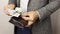 Solid man in gray jacket on white background takes three hundred US dollars bills out of wallet. Man counting banknotes