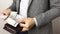 Solid man in gray jacket on white background takes three hundred US dollars bills out of wallet. Man counting banknotes