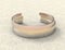 Solid metal bracelet in three colors on a stone table. Mockup close-up