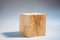 Solid oak cube on a gray background. Very shallow depth of field