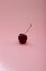 Solitary cherry in the center of a pink background