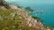 A solitary figure takes a view of Capri Island with iconic sea stacks Faraglioni. Perched on the mountainous terrain