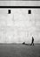 Solitary man walking beside a minimalist building with small windows. Generative AI