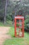 Solitary Red Telephone Booth in a Forest Path