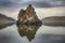 solitary rock formation jutting out of a tranquil lake