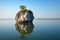 solitary rock formation jutting out of a tranquil lake