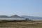 Solitary surfer carrying surf board walks along beach on coast Baja Californ