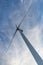 Solitary wind turbine, viewed from directly underneath, blue sky with clouds.