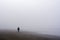 Solitary woman figure walking along a fog-shrouded beach