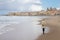 Solitary woman walking the beach of Cefalu in winter time, Sicily, south Italy.