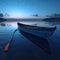 A solitary wooden boat on the calm surface of the lake under the tranquil blue hues of the twilight sky