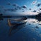 A solitary wooden boat on the calm surface of the lake under the tranquil blue hues of the twilight sky