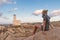 Solitary young female traveler watches a beautiful sunset over lighthouse and spectacular rock formations of Capo Testa