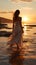 Solitude at sunrise, young woman in white dress strolls on beach