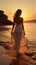 Solitude at sunrise, young woman in white dress strolls on beach