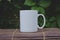 A solo blank white coffee mug on the bamboo table in the garden