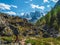 Solo hiking with a large backpack in the mountains. A man climbs a rocky mountain slope. In the background is a dome of snow-