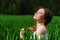 Solo outdoor activities. Young brunette woman in white top sitting in green wheat field looking up and enjoying sun .