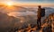 Solo traveler with a backpack standing on a mountain peak at sunrise