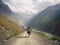 A solo traveler on a bicycle is going through a mountainous area.