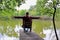 Solo traveling man sitting on the fisherman chair near the lake and forest