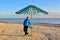 Solo traveling man under the sun umbrella on the beach with sea background