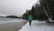 Solo woman traveler walking towards the frozen lake on a winte