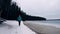 Solo woman traveler walking towards the frozen lake on a winter