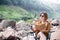 A solo woman traveller reading book while sitting on chair at waterfall