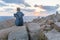 Solo young female traveler watches a beautiful sunset on spectacular rocks of Capo Testa, Sardinia, Italy.