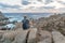 Solo young female traveler watches a beautiful sunset on spectacular rocks of Capo Testa, Sardinia, Italy.