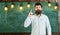 Solution concept. Bearded hipster in shirt, chalkboard on background. Guy has idea or warning shows index finger gesture