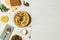 Solyanka, meat soup in a painted bowl on a light wooden table, with food for cooking. Top view, copy space