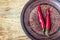 Some chili peppers on dark plate, fresh red ripe hot chilli on old wood board background with copy space, guinea pepper or bird pe