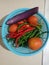 Some chilies and vegetables in a plastic basket