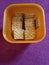 Some cute salty square cookies in an orange plastic box