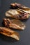 Some dehydrated organic beef ears made for dogs lying down on black background.