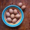 Some eggs in a bowl and some eggs on a table.