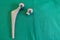 Some explanted hip prostheses lie spread out on a green surgical drape