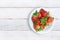 Some fresh red strawberries on a plate on a white wooden table of a rustic kitchen. Top view from above and empty copy space