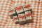 Some gift boxes wrapped in brown craft paper and tie red satin ribbon. Red carton hearts. Set of presents. Plaid material backgrou