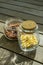 Some glass jars full of pasta with a cork stopper and another without a stopper and with dried chillies