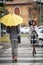 Some handsome and elegant young woman and man pass each other at a pedestrian crossing on a rainy day. Walk, rain, city