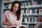 Some interesting information. Brunette girl in casual clothes having good time in the library full of books